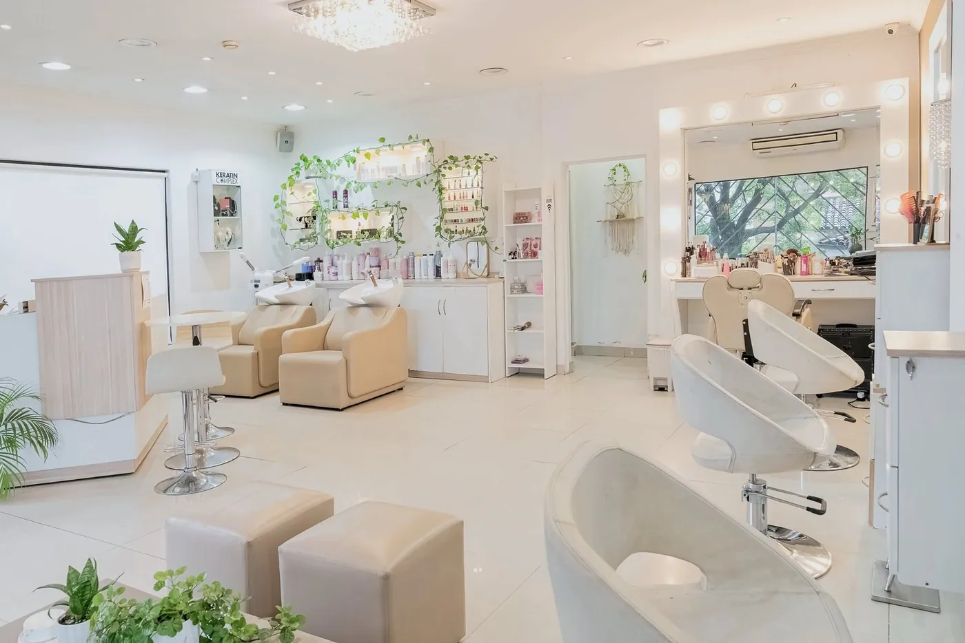 Salón principal con araña de cristal, sillones de lavado, estantes con enredadera y tocador de maquillaje con luces